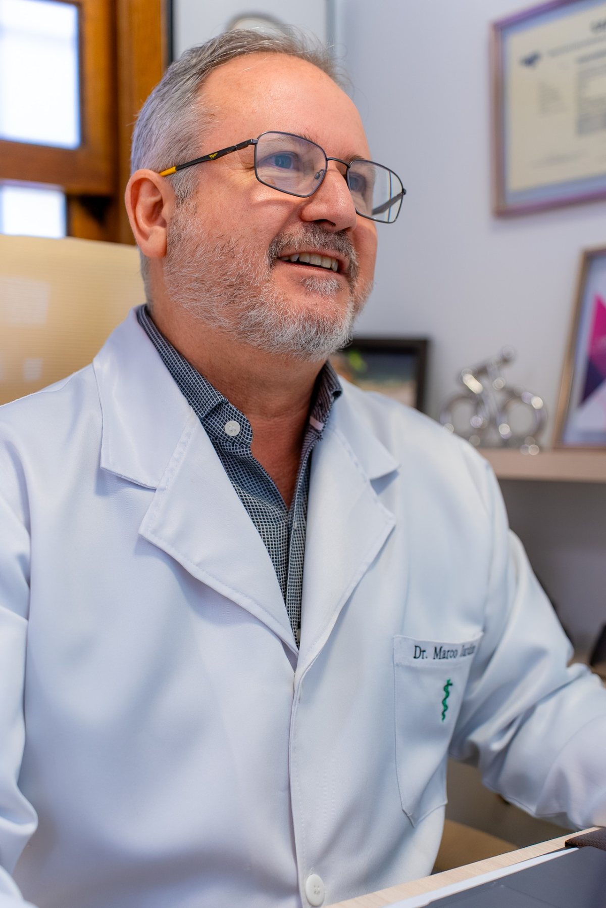 Dr. Marco Jardim sorrindo em seu consultório no Sion, Belo Horizonte